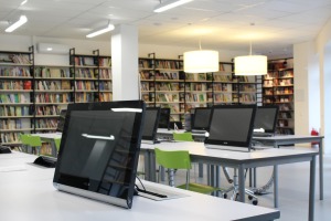 Image of computer monitors on tables in a library setting.